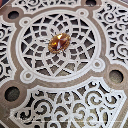 Prikaz pozivnice sa šampanj kovertom i ukrasnim omotačem na preklop koji je sastavljen od više papira, a jedan sloj papira je laserski izrezan. Omotač na sredini ima ukrasni kamenčić, a unutar njega se nalazi još jedan umetnuti sedef bež papir na kojem je odštampan tekst u crnoj boji. Pozivnica je kvadratnog oblika, smeđih i bež tonova sa akcent narandžastim ukrasnim kamenom.