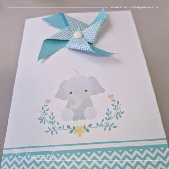 Prikaz dječije pozivnice na preklop napravljene od bijelog mat papira. Na dnu unutrašnje i spoljašnje strane nalazi se ukrasna bordura zig-zag šablona u tirkiznoj boji. Na obje strane je prisutna i ilustracija slončića sa cvjetnim ukrasima. Pozivnica na svojoj spoljašnjoj, naslovnoj strani, ima ukras vjetrenjače od papira u tirkiznoj boji pričvršćenog plastičnom nitnom.